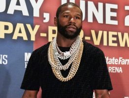 A photo of Floyd Mayweather in a black t-shirt wearing many gold chain necklaces