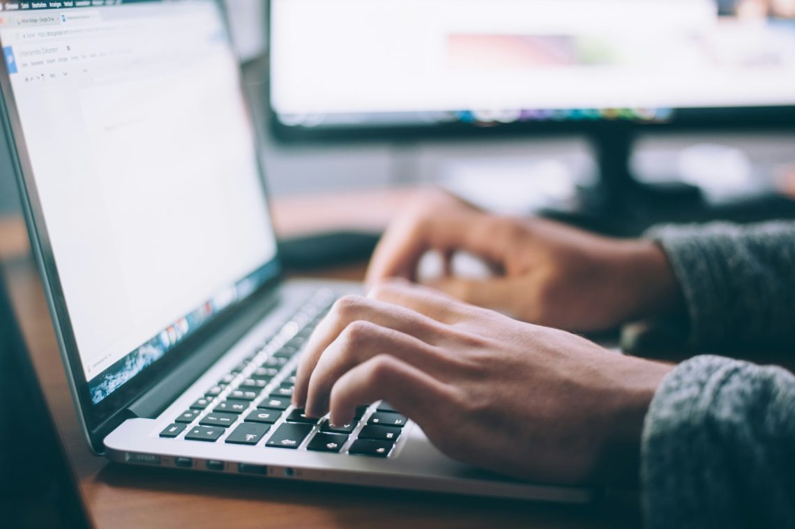 Close up of someone's hands typing on a laptop keyboard