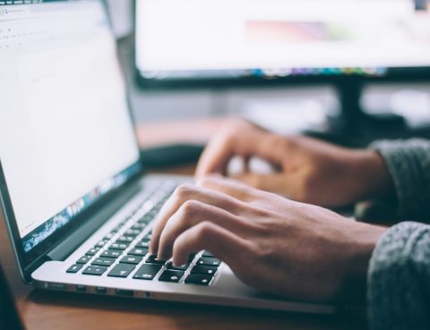 Close up of someone's hands typing on a laptop keyboard