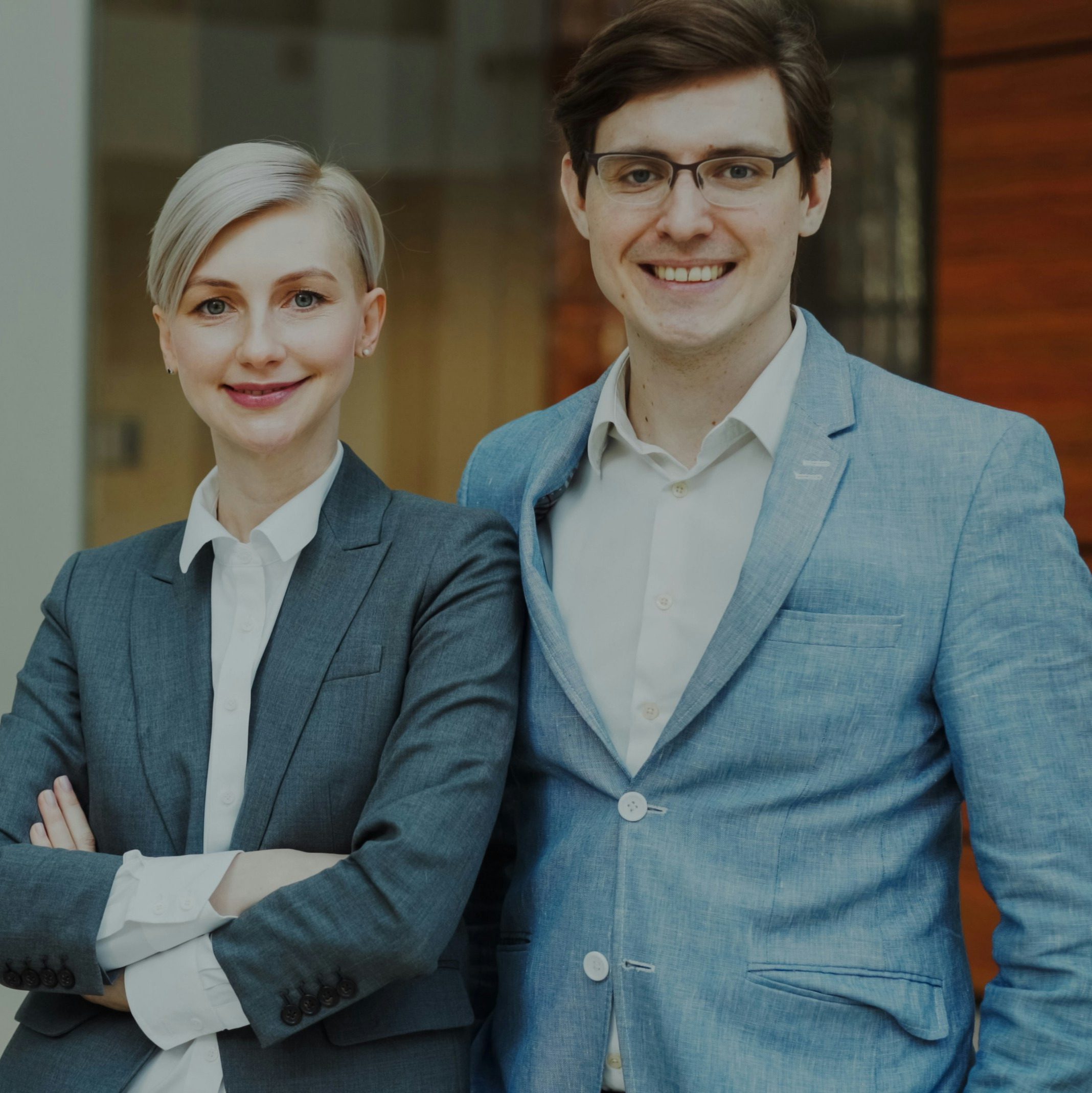 a professional woman and man wearing business attire and smiling at the camera