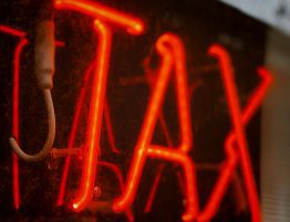 A read neon sign on a window that says "tax"