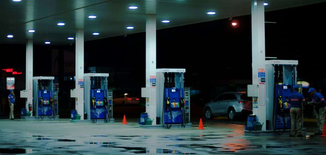 rows of gas pumps at a gas station at night