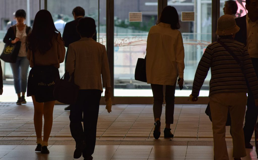 Photo of office workers exiting a building taken from behind them
