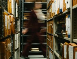photo of blurred woman walking past shelves full of files