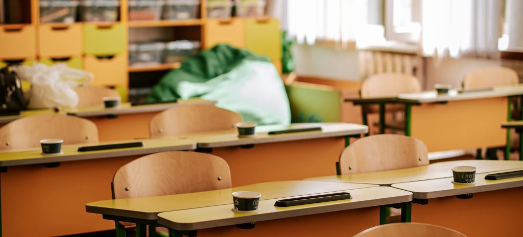 wooden desks in an empty, well lit classroom